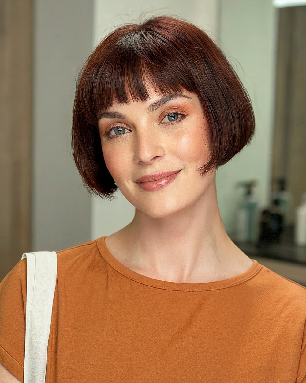 Chic French bob with short bangs on smooth auburn hair for a classic Parisian finish