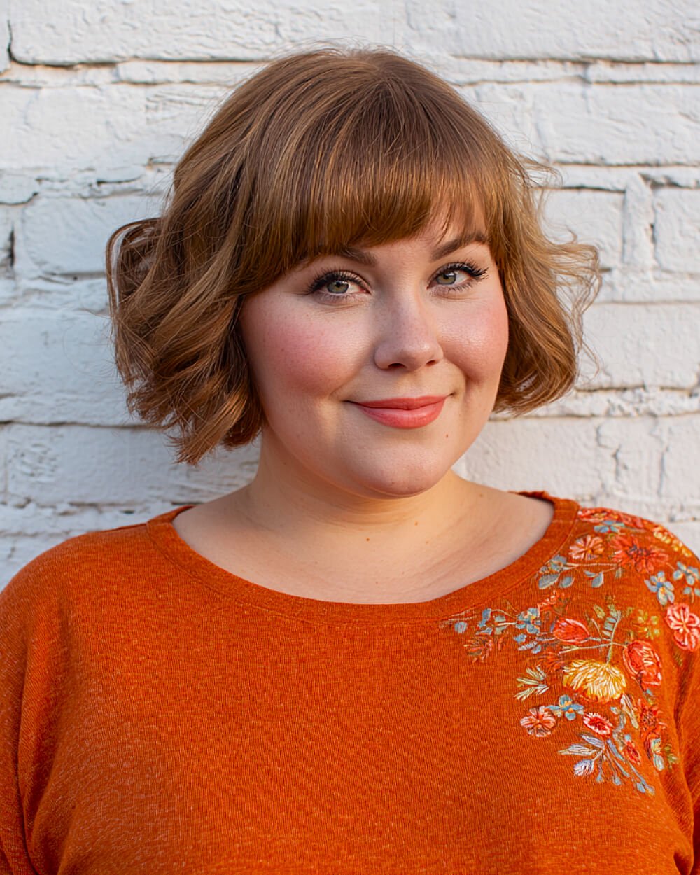 Short textured bob with full blunt bangs for round faces